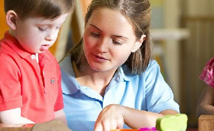 Teacher showing child how to play with toy