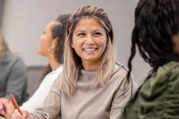 Mid adult Filipino businesswoman attends board meeting with diverse colleagues