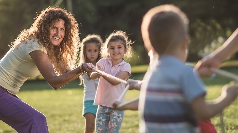 Educator and children playing tug-of-war